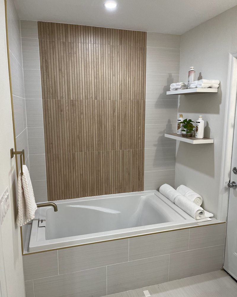 Finished bathroom with a wood-slat feature wall, soaking tub and brushed-gold fixtures