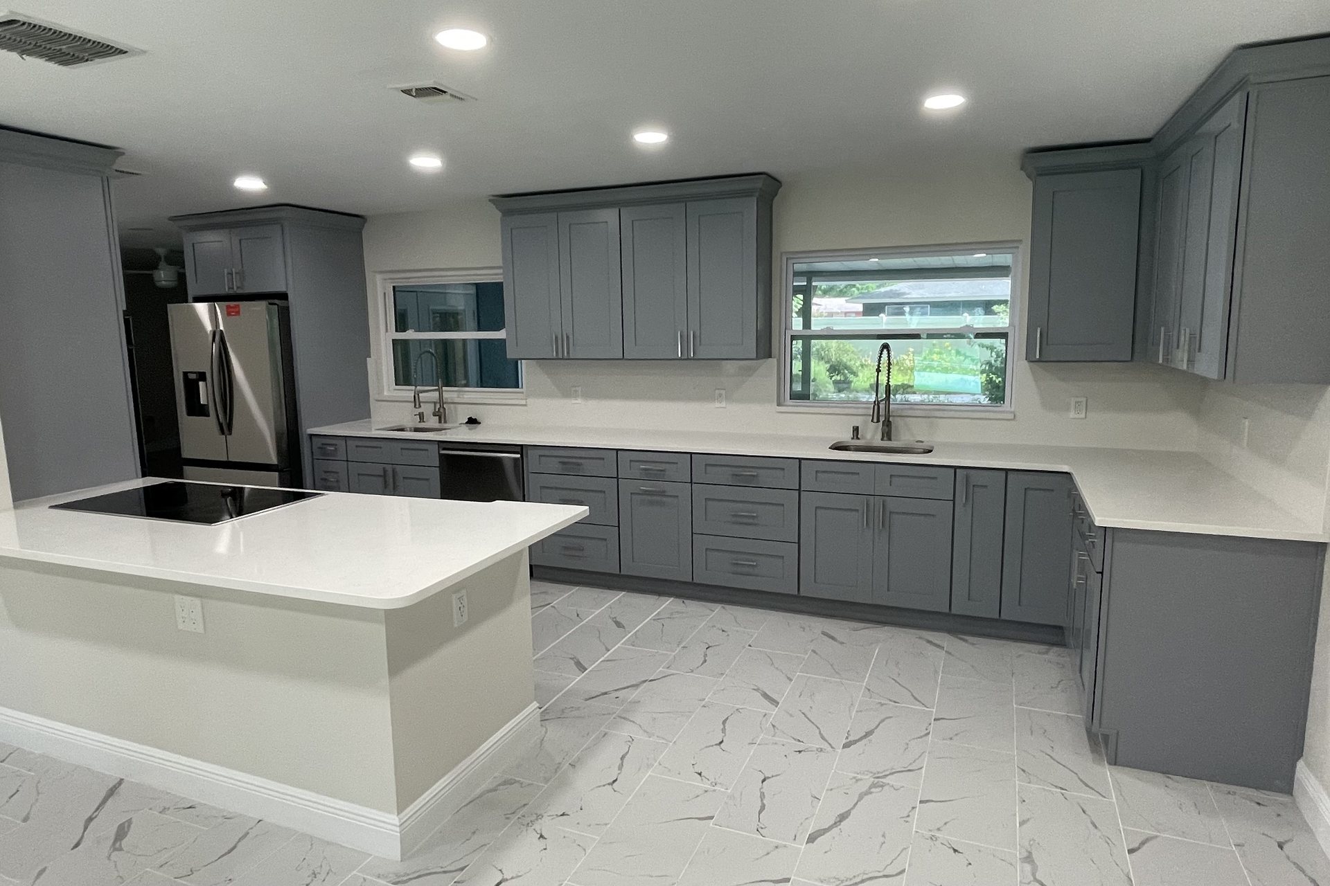 Renovated kitchen with white cabinetry, a marble island and pendant lighting