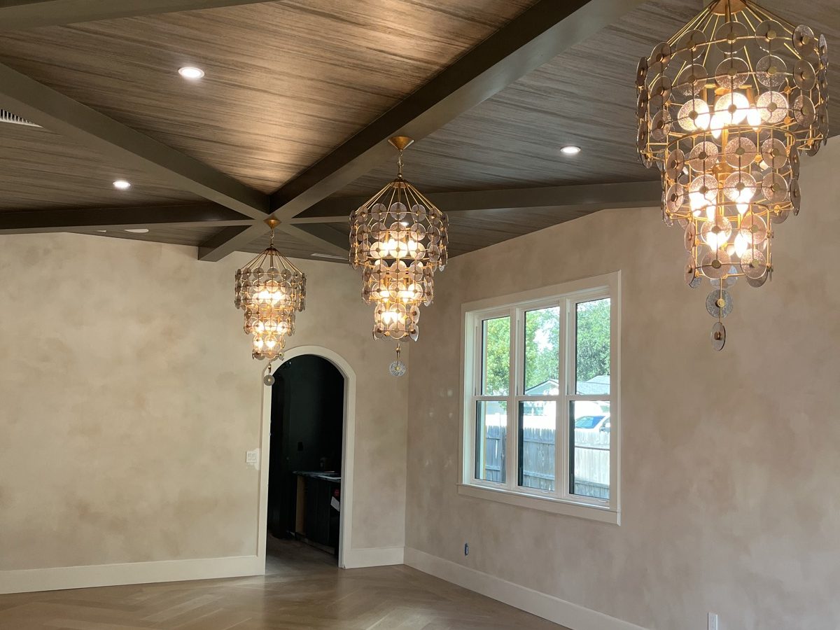 Vaulted great room with a wood-plank ceiling and layered chandeliers