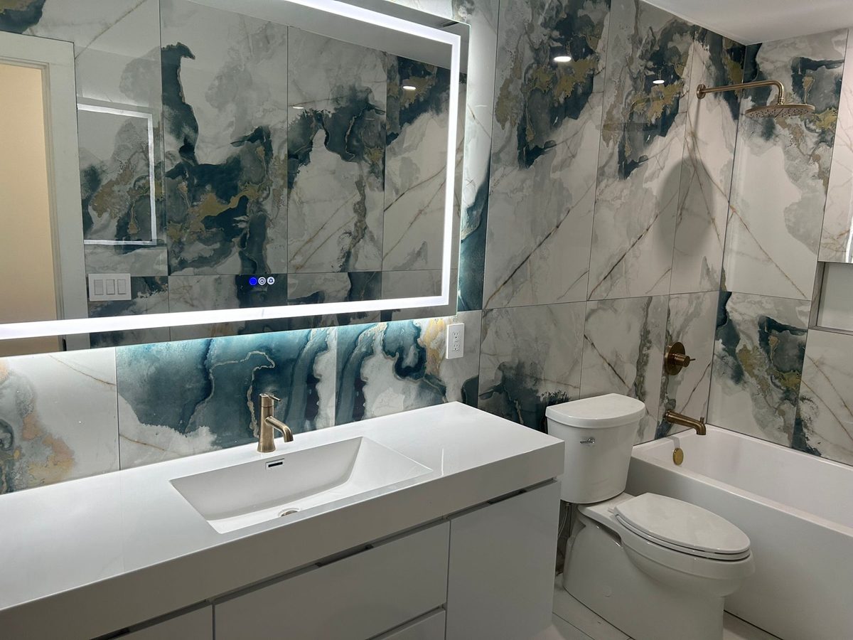 Bathroom with a dramatic blue-veined marble wall and a backlit mirror