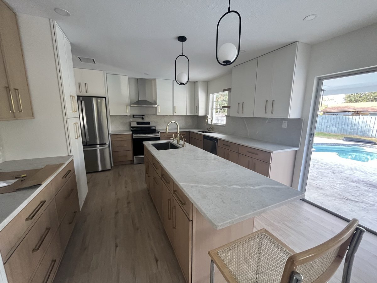 Wood-grain kitchen with a stone island overlooking the pool