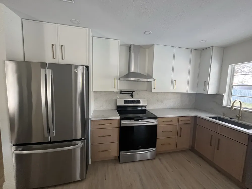 Two-tone kitchen with white upper cabinets, wood base cabinets and stainless appliances